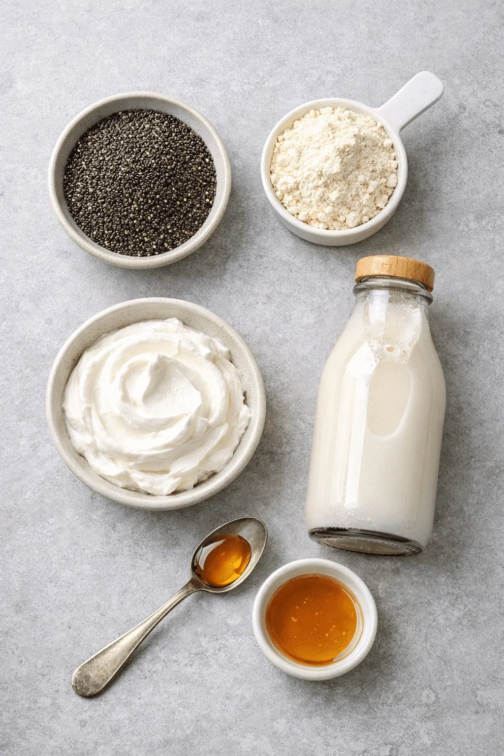 Portrait/Pinterest format () flat-lay overhead shot of all protein chia pudding ingredients arranged artfully on a light